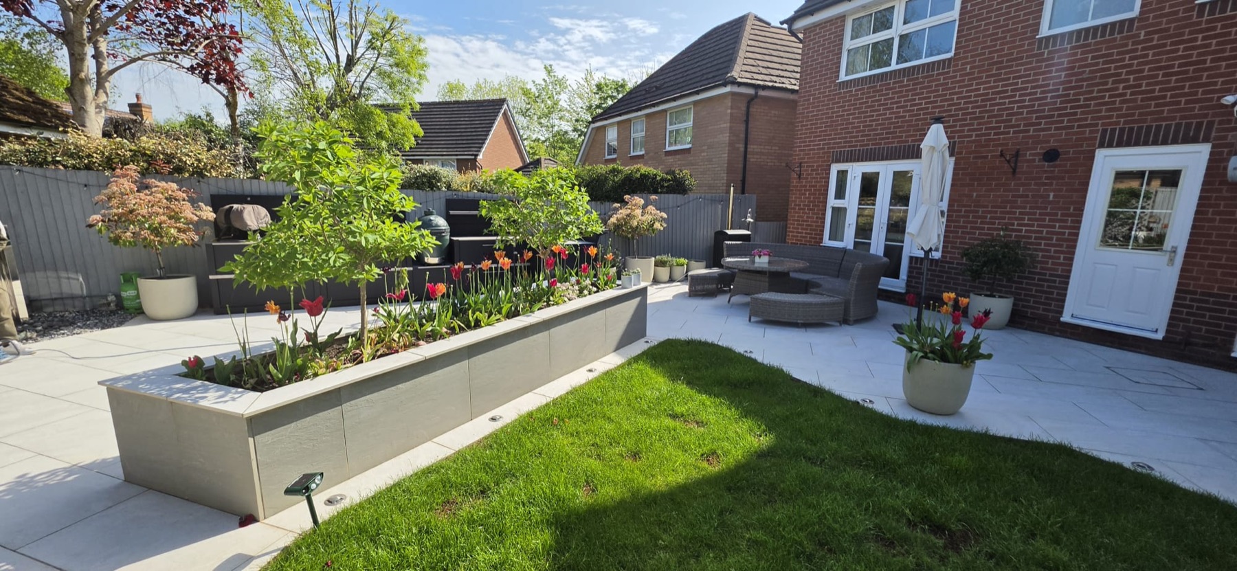 Landscaped garden with paved patio, raised planter and lawn