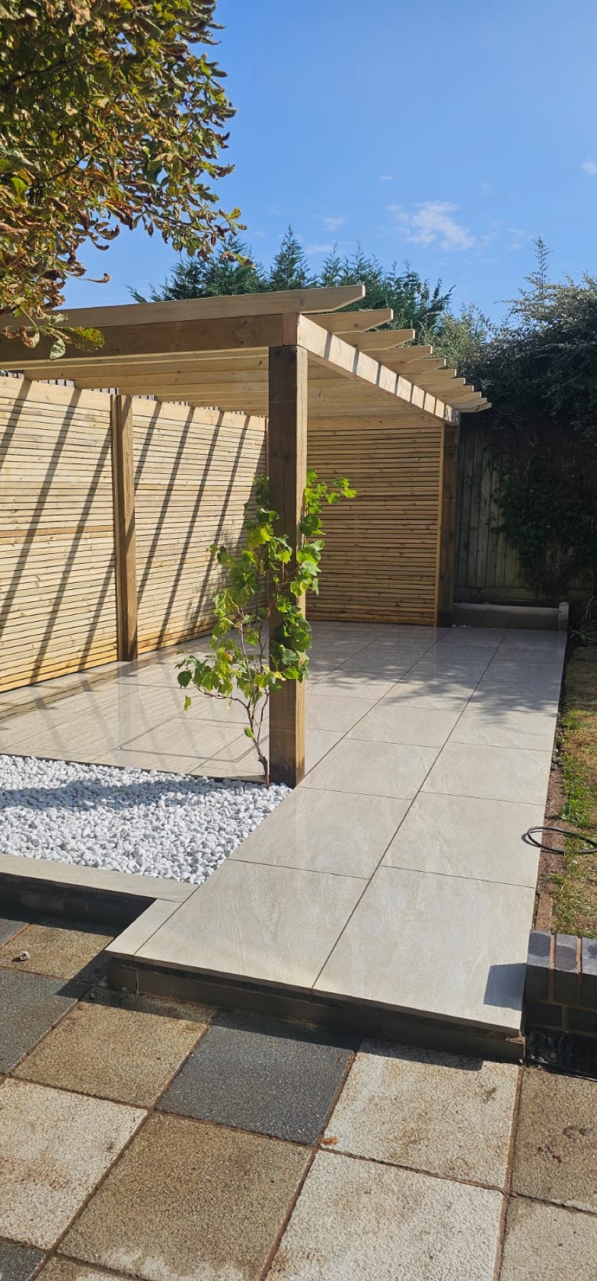 Modern timber slatted screening beside a paved pergola area
